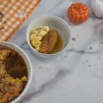Pumpkin pecan cobbler dessert in a bowl with ice cream with a drizzle of caramel sauce.