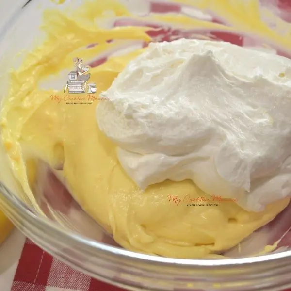 Banana cream with cool whip on top of it in a mixing bowl.