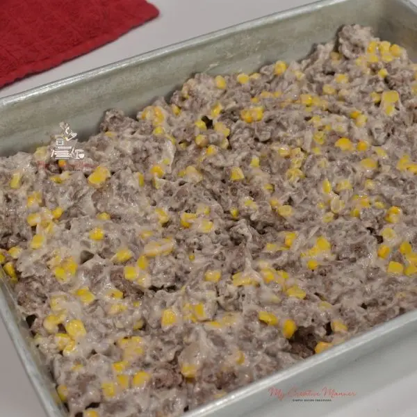 Ground beef, corn, and cream of mushroom soup in a baking dish.