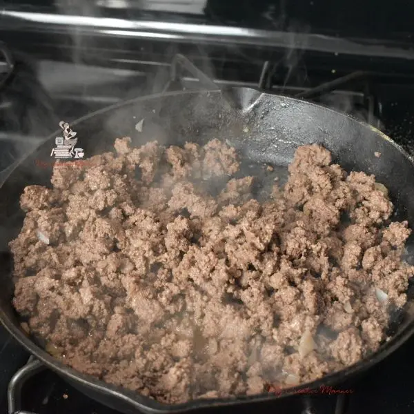 Ground beef in a frying pan being cooked for tater tot casserole.