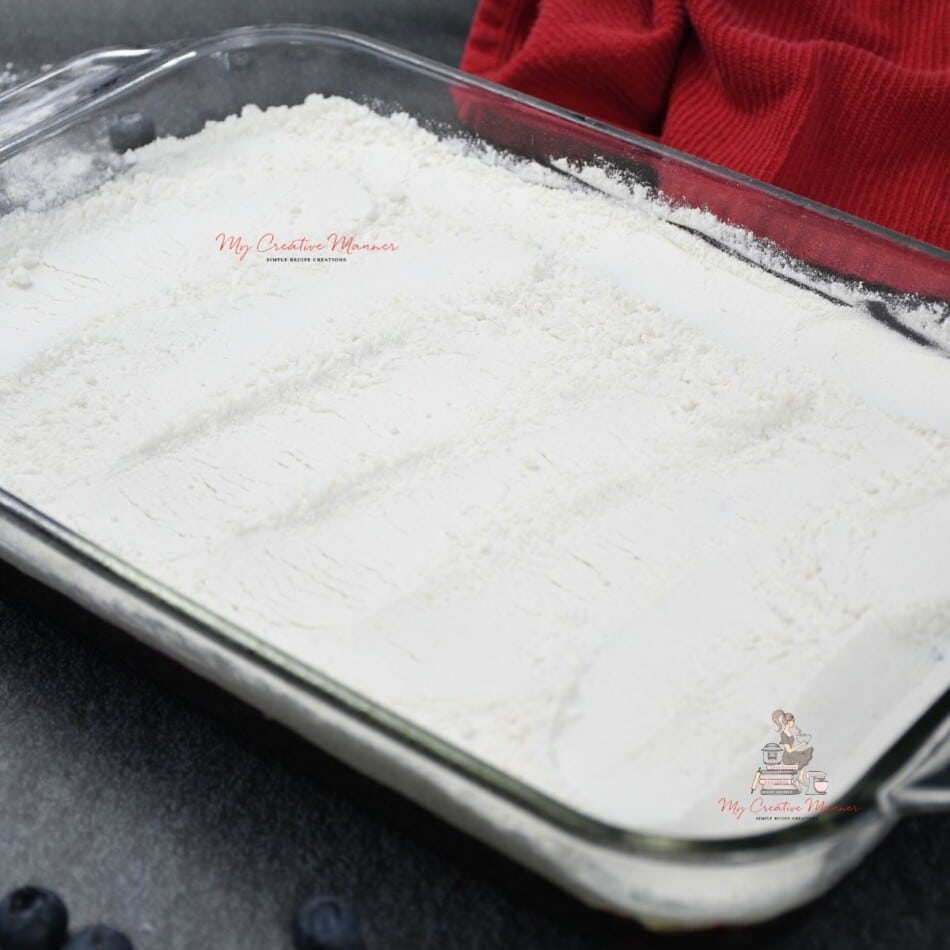 Box cake mix on top of pie filling in a baking dish.