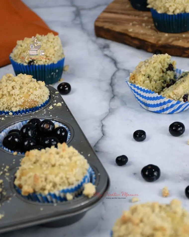 Blueberry Muffins in a muffin tin and on a counter top.