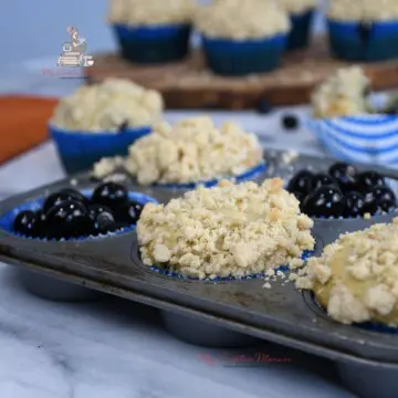 Banana blueberry muffins with crumb topping are in a muffin tray.