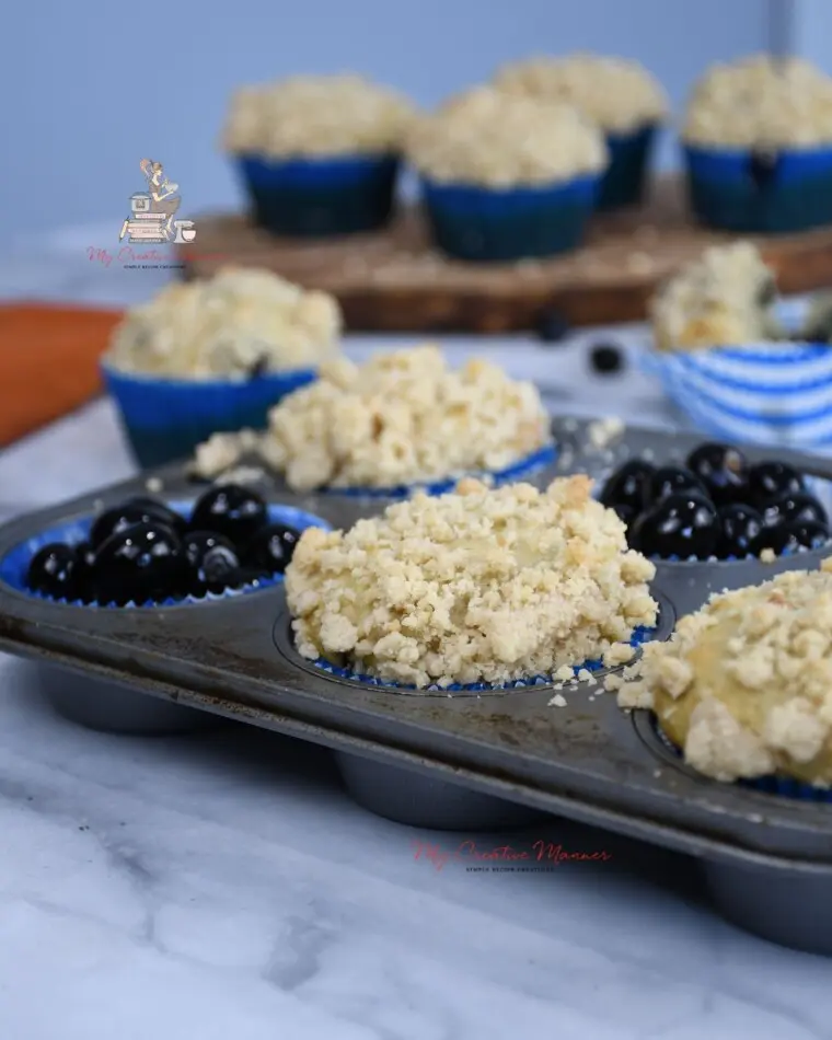 Banana blueberry muffins with crumb topping are in a muffin tray.