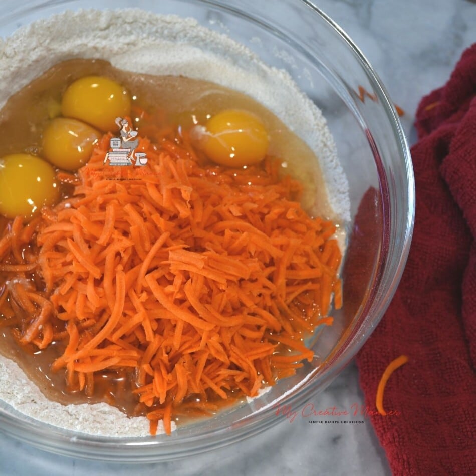 Carrots, flour, and eggs in a bowl.