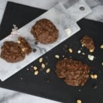 Candies on a marble platter with more nuts a clusters on a black palatter.