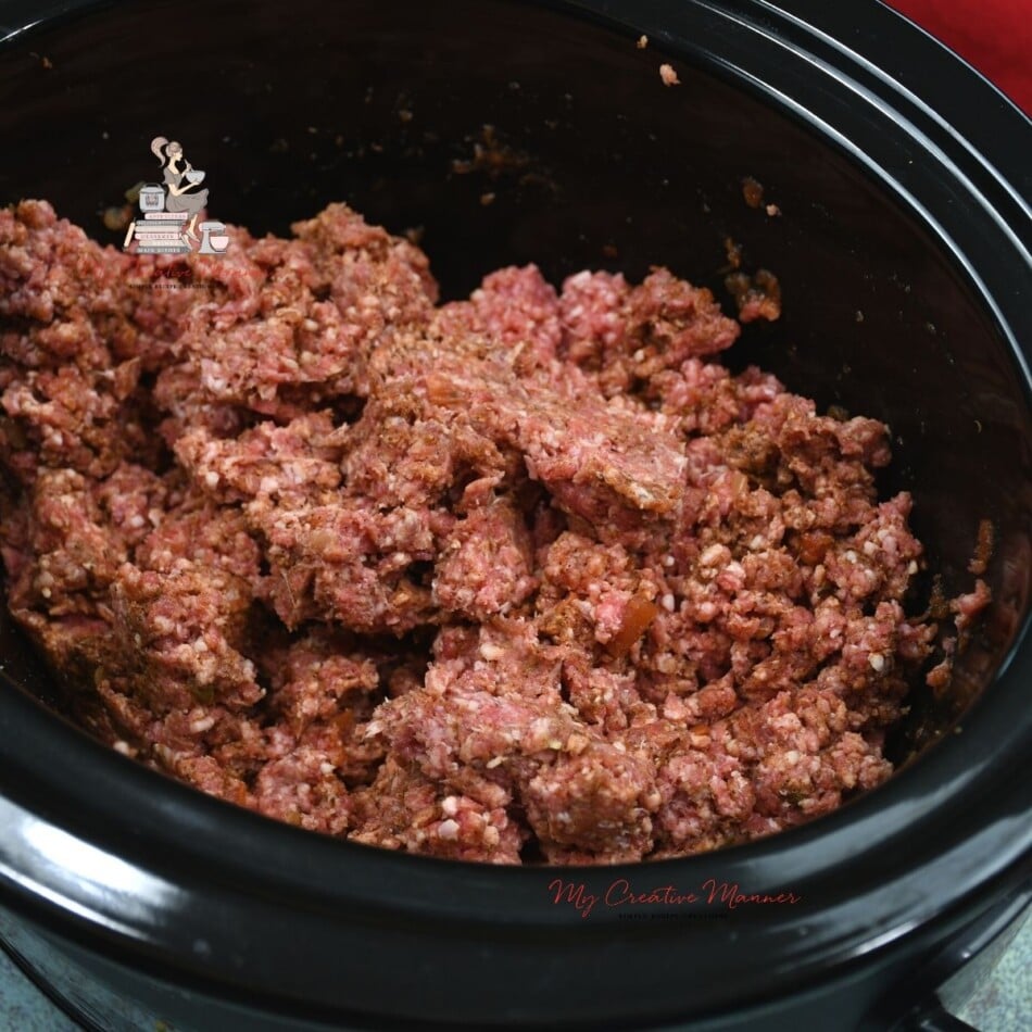 Mixed up ground beef in a slow cooker.
