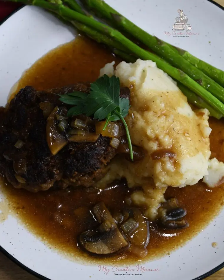 Salisbury steak with mushroom gravy on a plate with mashed potatoes. 