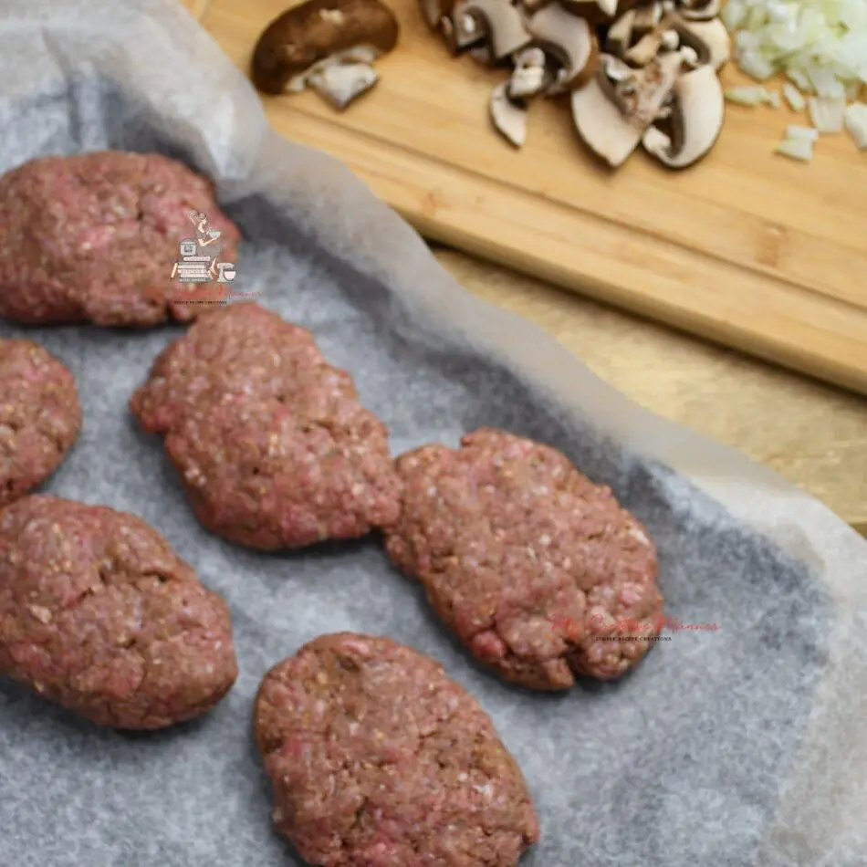 Raw ground beef in patties that are on wax paper.