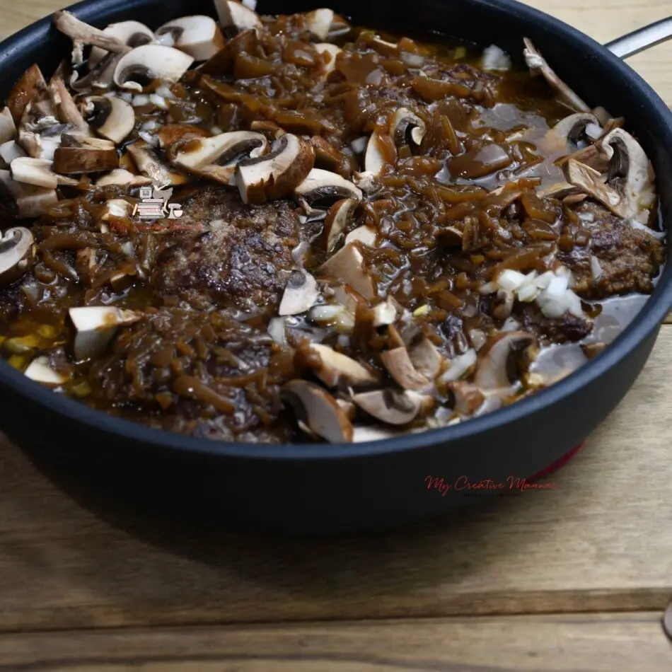 A frying pan that is full of the recipe that is coated with French onion soup and mushrooms.