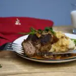 A fork that has some of the hamburger patty on it. With the rest of the recipe on a plate.