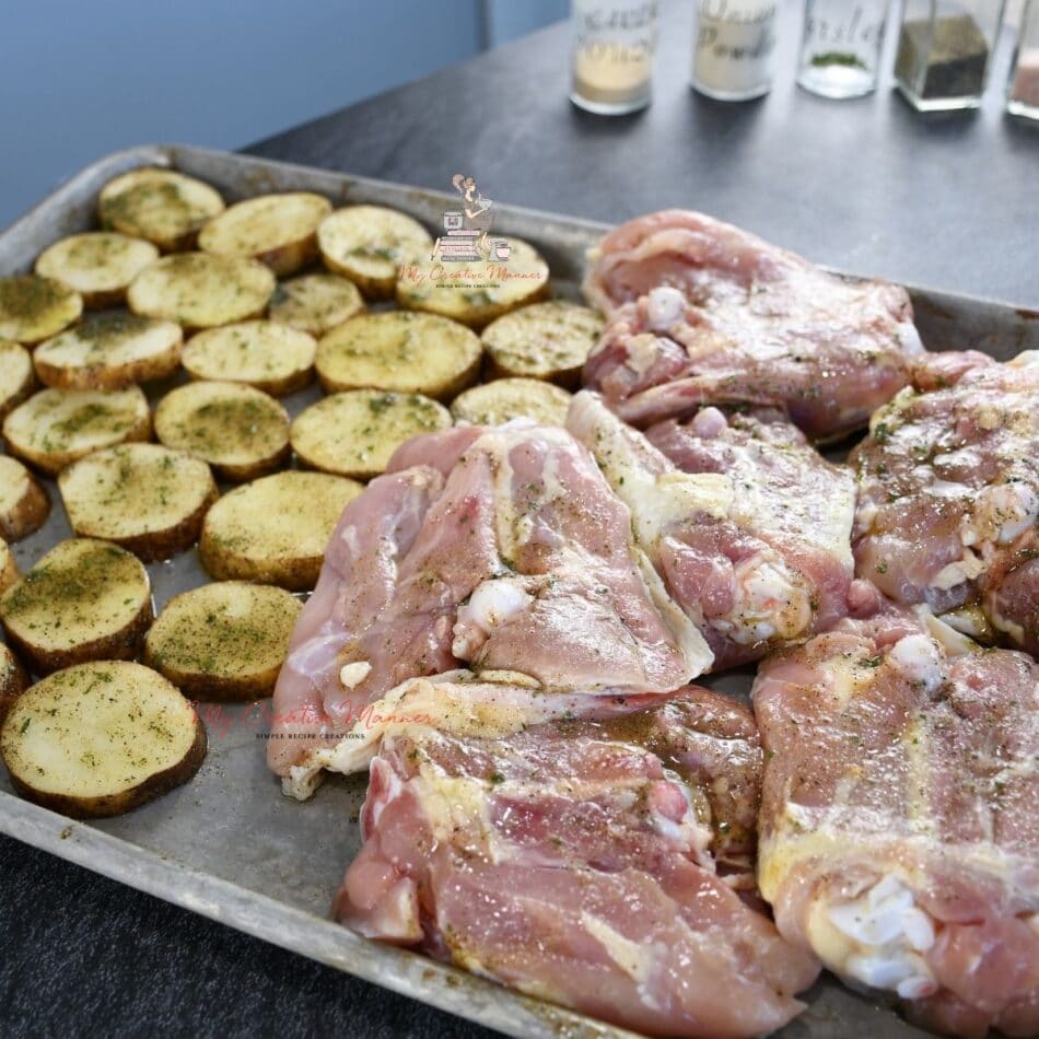 Uncooked chicken and potatoes on a sheet pan.