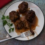 A plate with barbecue meatballs on it and a fork.