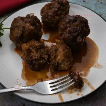 A plate of easy to make bbq meatball recipe and a fork that has part of a meatball on it.