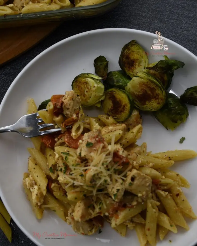 Chicken with feta on a fork with more on the plate and Brussel sprouts.