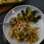 A plate with Brussel Sprouts and the feta cheese pasta on it with a fork.