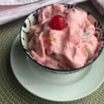 Strawberry jello fluff salad in a bowl with a spoon next to it.