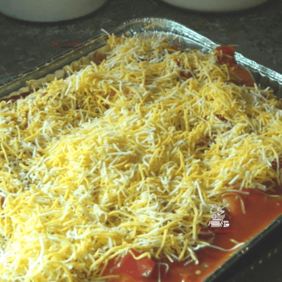 Wet burrito recipe that is covered in cheese in a foil pan.