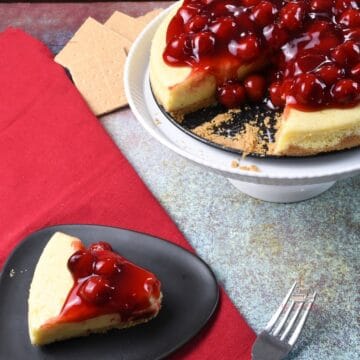 A plate with the cheesecake on it and the rest on a cake stand.