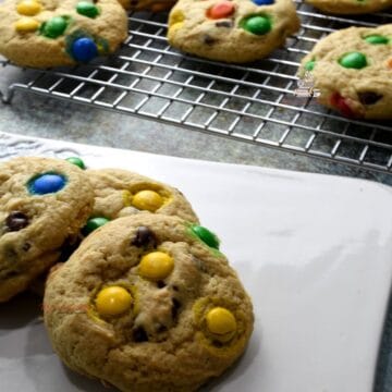 M&M Cookies on wax paper and more on a cooling rack.