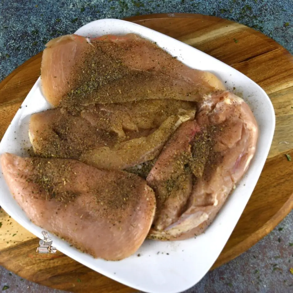Raw chicken breast on a white plate.