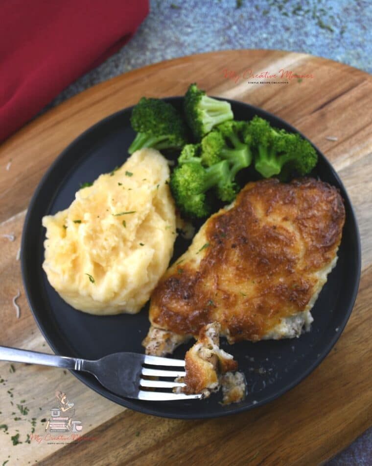 Parmesan Chicken with mayo on a plate with potatoes and broccoli.