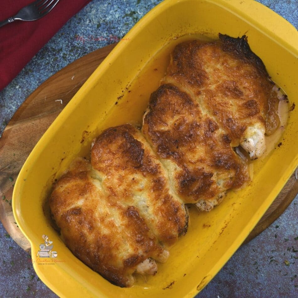 Parmesan chicken with mayo recipe that is baked in a yellow baking dish.