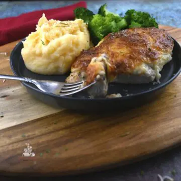 A fork that is on a grey plate with mayo chicken parmesanon it. Mashed potatoes, broccoli, and more meat are on the plate.