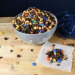A bowl filled with trail mix and more next to it on wax paper.