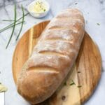 A whole French loaf on a cutting board.
