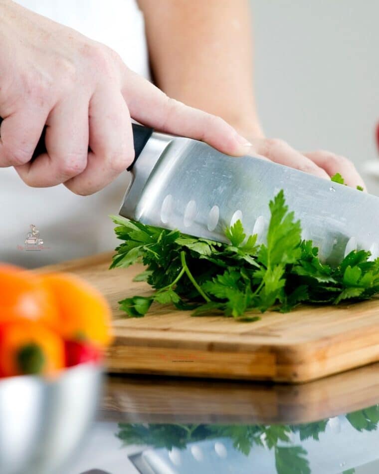 A knife chopping parsley for a demonstration of the cooking term chop.