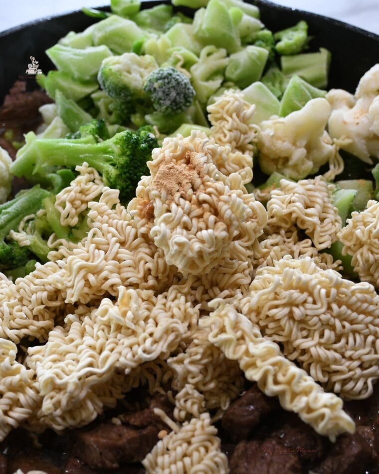 Ramen noodles and frozen veggies in a skillet.