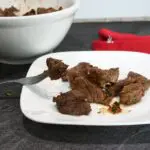 Steak bites on a white plate.