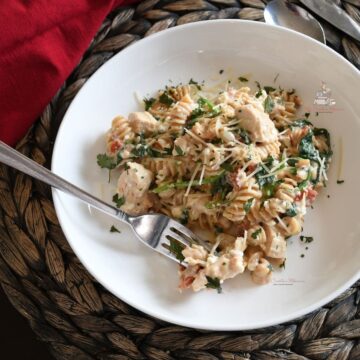 Healthy pasta recipe with chicken in a white bowl with a fork.