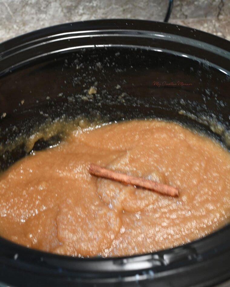 Pear apple butter with a cinnamon stick on it in a crockpot.