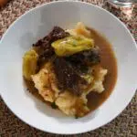 Mississippi roast over mashed potatoes in a white bowl.