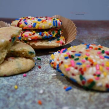 Sugar cookies with sprinkles stacked on top of each other.