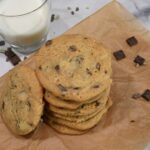 The recipe is on a brown paper with a glass of milk next to it.