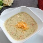 Broccoli cheese soup that is in a white bowl.