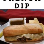 French dip sandwich on a white platter with chips and au just sauce.