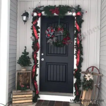 A front door to a porch that is all decorated in farmhouse Christmas decorations.