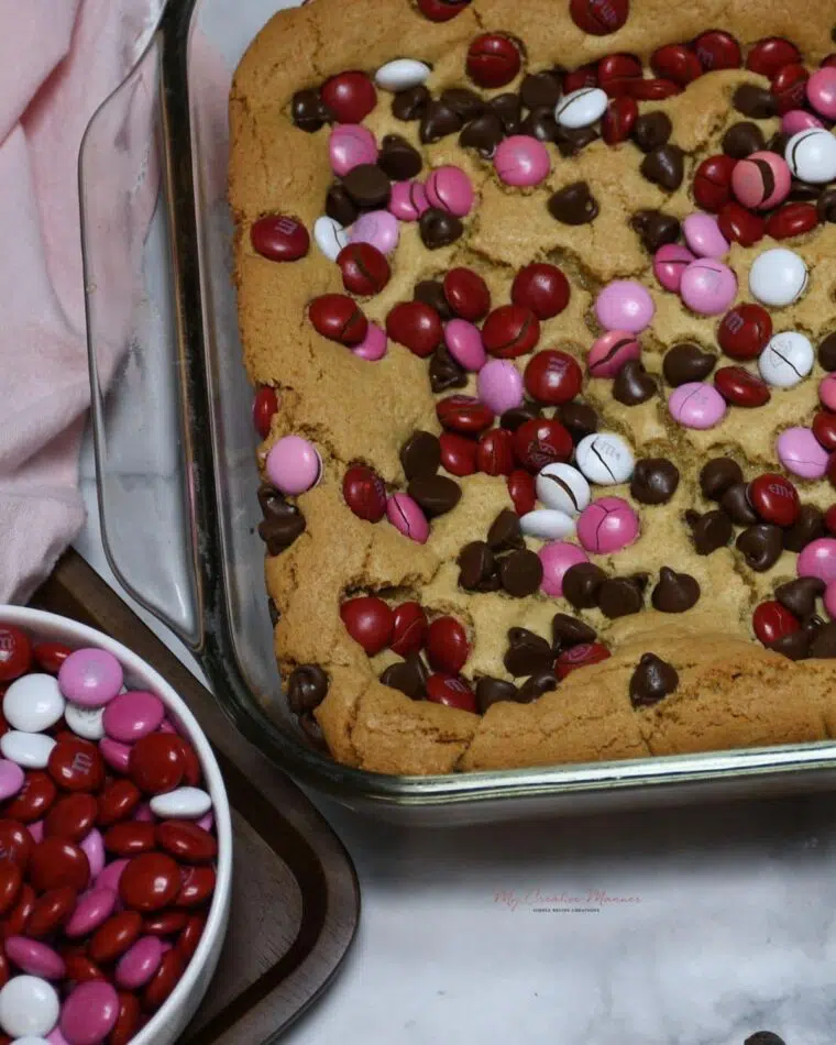 Valentine bars in a baking dish with a bowl of M&M's next to it.