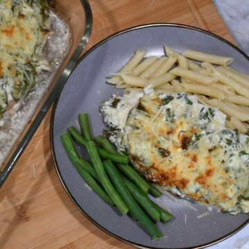 A keto spinach artichoke chicken casserole recipe on a plate with green beans and noodles.