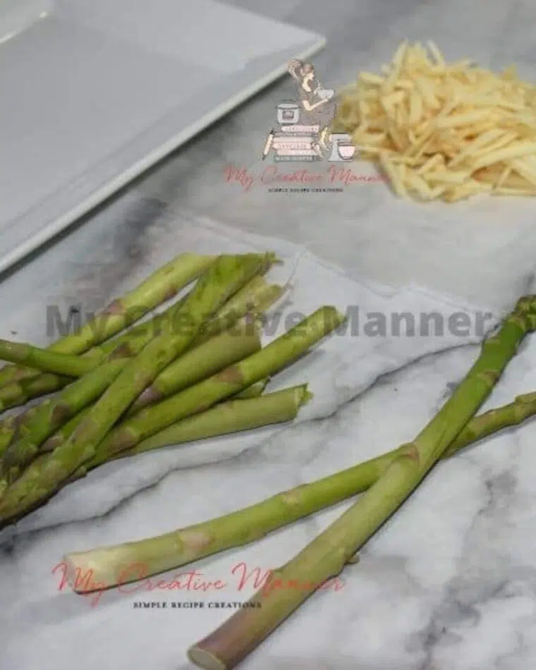 Fresh asparagus on a counter with grated cheese behind it.