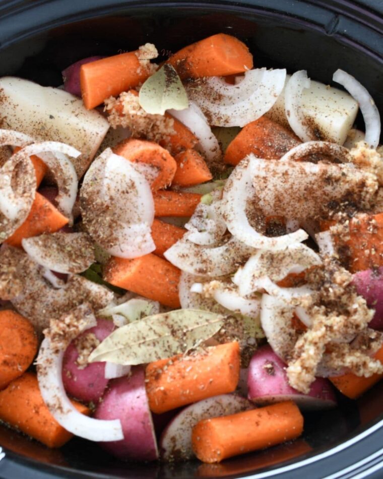 A crockpot filled corned beef and vegetables with beer. 