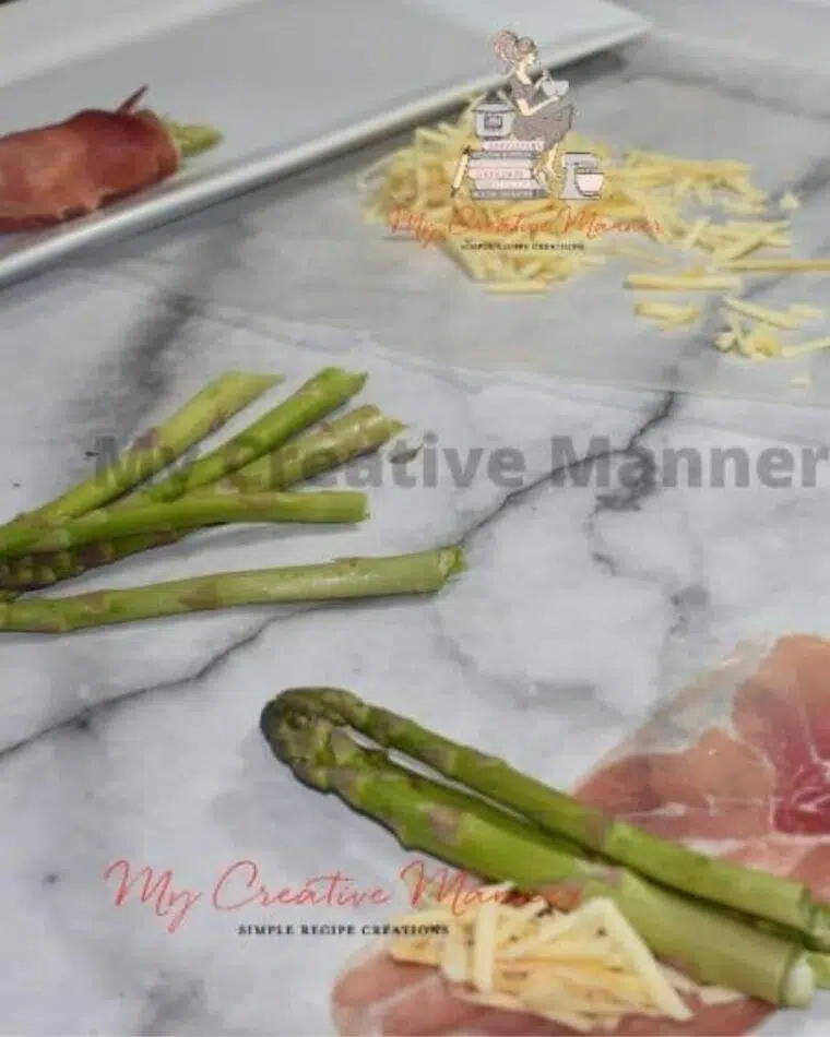 Fresh asparagus being wrapped in ham with cheese.