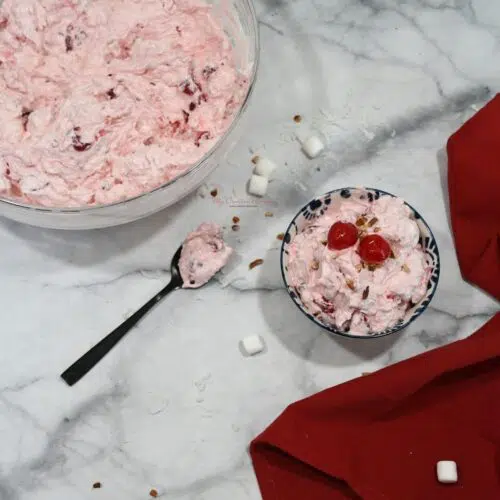 Overhead shot of cherry fluff salad in a small bowl, a larger bowl, and some on a spoon.