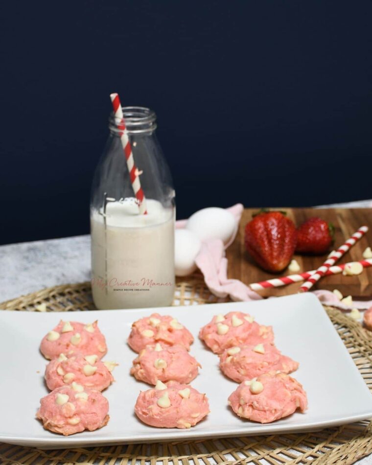 Strawberry cake mix cookies on a plate with a glass of milk next to it.