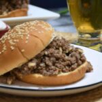 A close up of a bumbo burger that is made with chicken gumbo soup on a white plate.