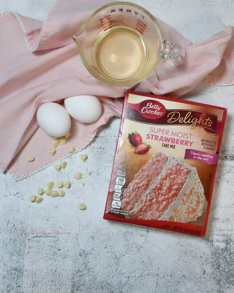 A strawberry box cake, eggs, white chocolate chips, and oil for the cookies.